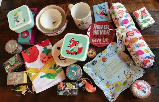 Selection of gift products on a desk: mug, boxes, tea towel, trinket boxes