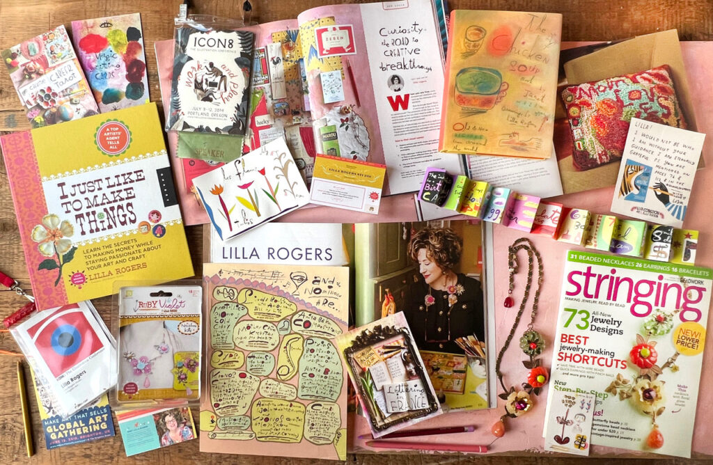 Magazines, books, cards and jewellery set out on a desk all by Lilla Rogers